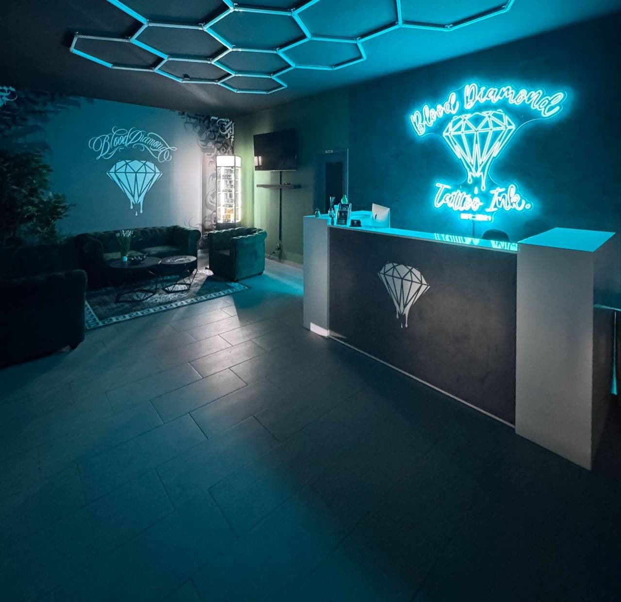 Empfangsbereich von Blood Diamond Tattoo Ink. mit Lounge und Neonlogo.